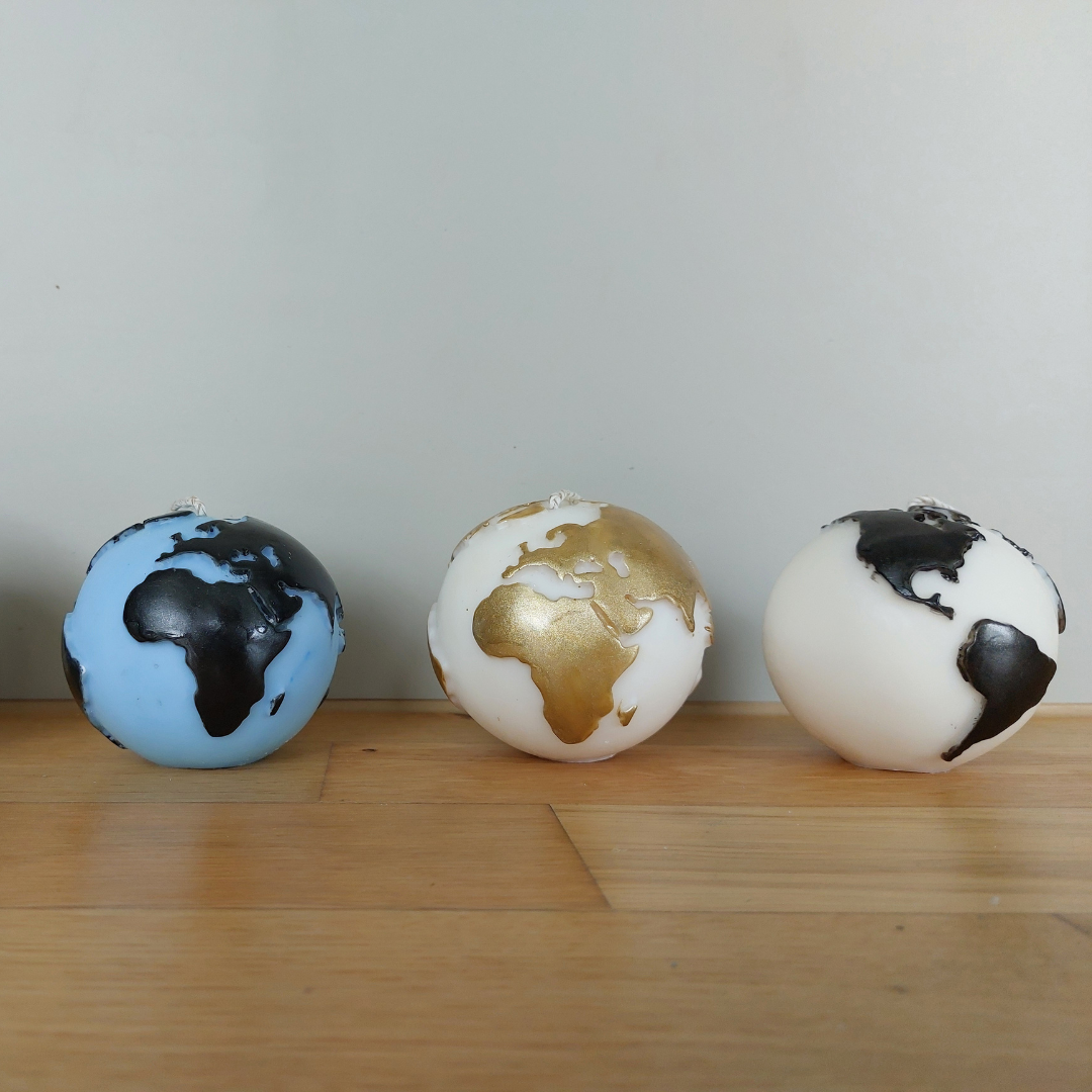 Handgegossene Globus-Kerze aus europäischem Rapswachs in vier Farbkombinationen – Weiss/Gold, Blau/Gold, Weiss/Schwarz, Blau/Schwarz, gefertigt im Atelier Romanshorn